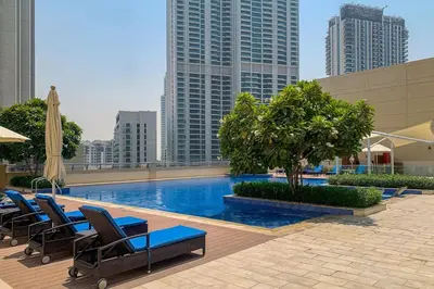 a pool with chairs and a tree and buildings at LUXE | Luxury 2BR | Creek View | Modern & Cozy in Dubai