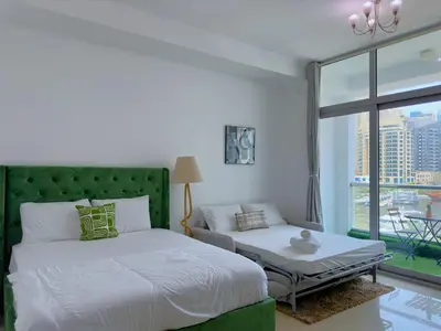 a bedroom with a green headboard and a bed and a window at Luxury Studio w Marina View & New Furnishings for 4 Pax in Dubai