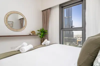 a bedroom with a bed with a mirror and a window at Luxury High Floor Apartment with Downtown Boulevard View Opposite Dubai Mall in Dubai