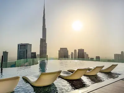 a pool with chairs on the roof of a building at 5 Star High Rise Luxury Apartment, Infinity Pool With Stunning Burj View - Brand New Apartment in Dubai