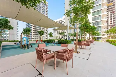 a patio with tables and chairs and a playground at Silkhaus 1BDR Marina Vista with Private Beach Access in Dubai
