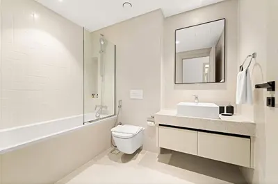 a bathroom with a sink and a toilet and a mirror at Silkhaus 1BDR Marina Vista with Private Beach Access in Dubai