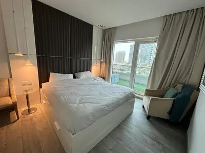a bedroom with a bed and a chair and a window at Damac canal views building in Dubai
