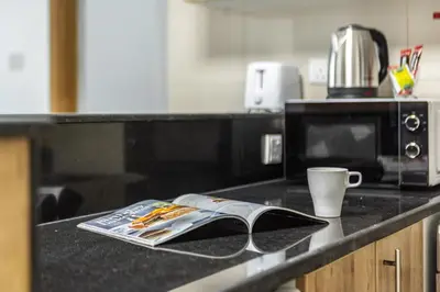 a kitchen counter with a book and a cup of coffee at ShoresInn - Luxury 1BR with Marina View in Dubai