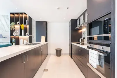 a kitchen with brown cabinets and a sink at Elegant & Cozy 2BR Home in the Heart of Downtown in Dubai