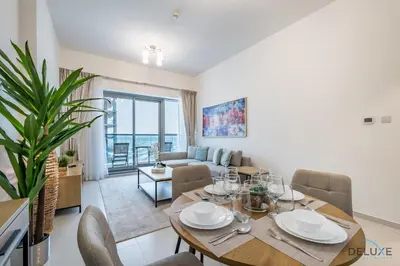 a dining room and living room with a table and chairs at Stylish 1BR Apartment at Orchid Residence, Al Barsha South by Deluxe Holiday Homes in Dubai