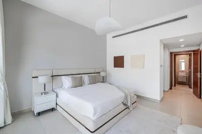 a white bedroom with a large bed and a table at 1BR with Study City View Bay Square in Dubai