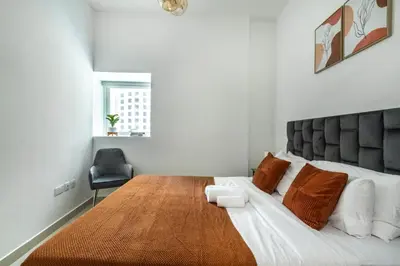 a bedroom with a large bed with a wooden table at ShoresInn - Serene Retreat with Waterfront Views in Dubai