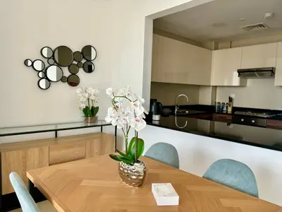 a dining room table with a vase of flowers on it at Sparkle Tower Panoramic Marina View 1BR in Dubai