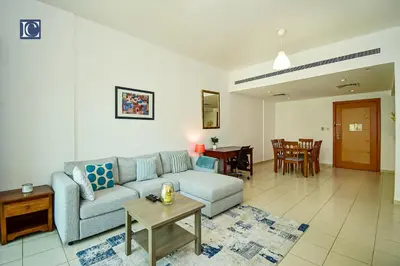 a living room with a couch and a table at Luxury Escapes - Spacious 1BR with Pool view - Ghozlan 2 The Greens in Dubai