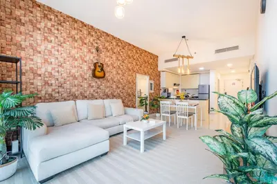 a living room with a couch and a brick wall at Premium 1BR at DAMAC Hills Loreto 1B in Dubailand by Deluxe Holiday Homes in Dubai