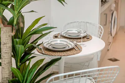a white table with plates and glasses on it at Modern and Cozy Studio at Seven Palm Prime Location in Dubai