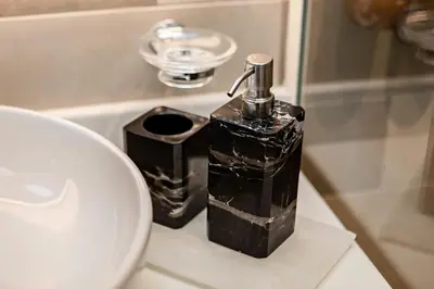 a black soap dispenser on a bathroom counter next to a sink at Modern and Cozy Studio at Seven Palm Prime Location in Dubai