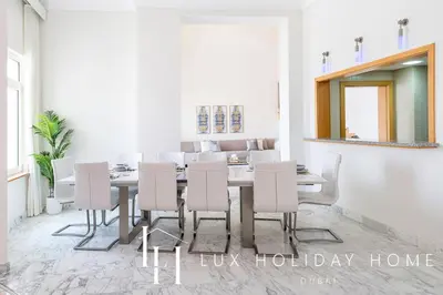 a dining room with a table and white chairs at LUX The Shoreline Palm Island Penthouse in Dubai