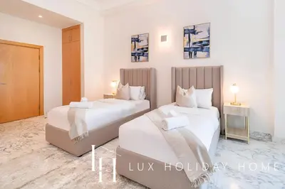 two white beds in a room with two tables at LUX The Shoreline Palm Island Penthouse in Dubai