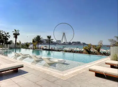 a large swimming pool with a ferris wheel in the background at La Vie Beach front JBR apartment by Happy Season in Dubai