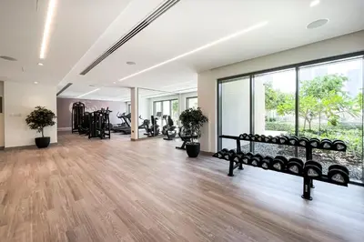 a gym with treadmills and benches in a room with windows at 1BR Burj Royale Near Dubai Mall Downtown in Dubai