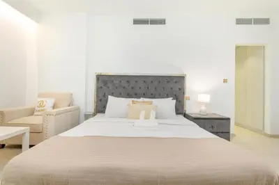 a white bedroom with a large bed and a chair at Vacay Lettings - Spacious 3 Bedroom at JBR walk in Dubai