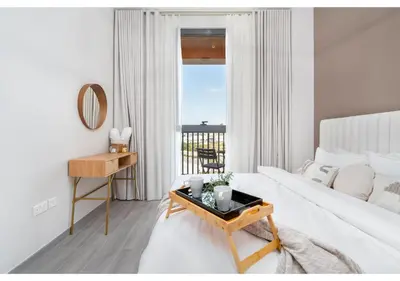 a white living room with a bed and a table at Trendy & Cozy 1BR Midtown 20 mins to Expo City by Vibel in Dubai