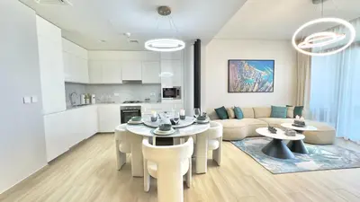 a kitchen and a living room with a table and chairs at Luxury 2BR w Waterfront View & Smart Controls by Vibel in Dubai