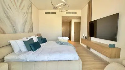 a bedroom with a white bed and a flat screen tv at Luxury 2BR w Waterfront View & Smart Controls by Vibel in Dubai