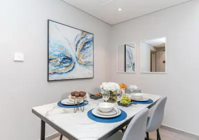 a dining room with a table with chairs and a painting at Classy 1BR in Midtown Access All Dubai Spots by Vibel in Dubai