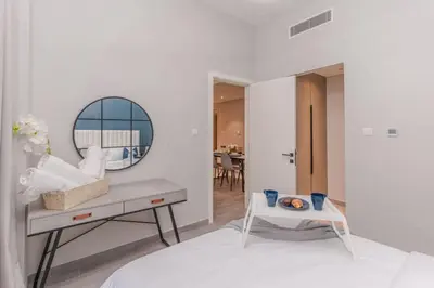 a white room with a table and a mirror at Classy 1BR Midtown Stay Near Miracle Garden by Vibel in Dubai