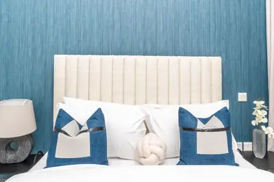 a bed with white pillows and a blue wall at Classy 1BR Midtown Stay Near Miracle Garden by Vibel in Dubai