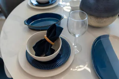 a table with blue plates and a bowl with a napkin at Stylish 1BR w City Views Palace Creek Harbour by Vibel in Dubai