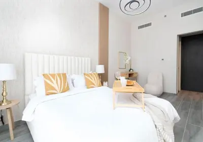 a white bedroom with a large bed and a table at Cozy 2BR Near Dubai Spots Midtown Dubai Access by Vibel in Dubai