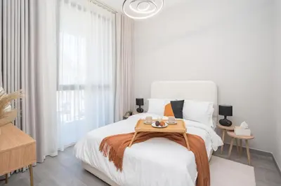 a white bedroom with a bed with a wooden tray on it at Cozy 1BR Midtown 20 Mins to Mall of Emirates by Vibel in Dubai
