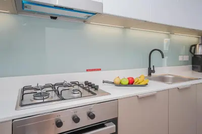 a kitchen with a stove and a bowl of fruit at Cozy 1BR Midtown 20 Mins to Mall of Emirates by Vibel in Dubai