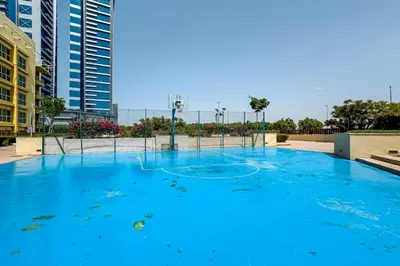 a large blue pool with a basketball hoop at 1BR The Greens Courtyard View in Dubai