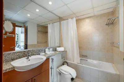 a bathroom with a sink and a toilet and a tub at 1BR The Greens Courtyard View in Dubai