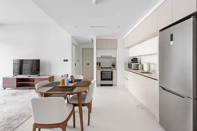a kitchen with a wooden table and white cabinets at Silkhaus Marina View 1BDR Private Beach Access in Dubai