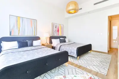 a bedroom with two beds and a rug at 2 BR with Maid's Next to Dubai Mall Mada Residences in Dubai