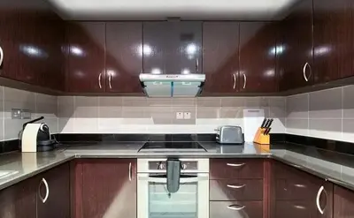 a kitchen with wooden cabinets and a stove top oven at Luxury Holiday Home, Spacious 1 bedroom, Burj Alarab full ocean view, located in Anantara the palm, Palm Jumeirah, Dubai in Dubai