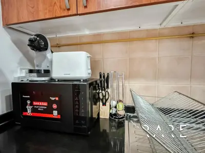 a microwave on top of a counter in a kitchen at Rare Holiday Homes - Near City Center Ma'eisem - Pool view - Crescent Tower A - R706 - IMPZ in Dubai