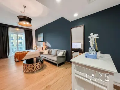 a living room with a couch and a table at Rare Holiday Homes - Near City Center Ma'eisem - Pool view - Crescent Tower A - R706 - IMPZ in Dubai
