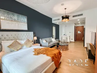 a bedroom with a large bed and a living room at Rare Holiday Homes - Near City Center Ma'eisem - Pool view - Crescent Tower A - R706 - IMPZ in Dubai