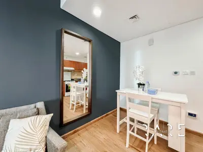 a living room with a table and a mirror at Rare Holiday Homes - Near City Center Ma'eisem - Pool view - Crescent Tower A - R706 - IMPZ in Dubai