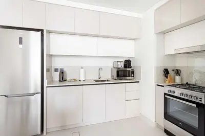 a kitchen with white cabinets and a stainless steel refrigerator at Silkhaus Mid Floor Marina Vista with Private Beach in Dubai