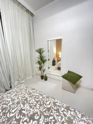 a white bedroom with a bed and a mirror at Contemporary 1BR condo with pool at Creek Harbour in Dubai