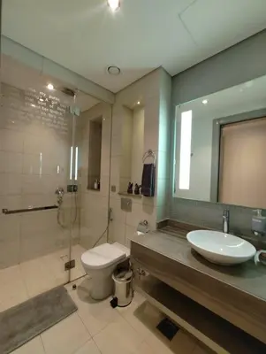 a bathroom with a sink and a toilet and a mirror at 2BR Tower D Paramount Apartment in Dubai