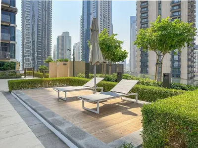 two benches and an umbrella in a park with buildings at 2BR Burj Khalifa & Fountain Views Burj Crown 39th Floor in Dubai
