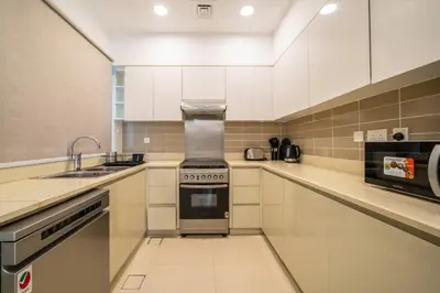 a kitchen with white cabinets and a stove top oven at NewArabian Dubai HillsMaple Villa in Dubai