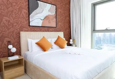 a bedroom with a bed with orange pillows and a window at Stunning 2 Bedroom Apartment Downtown Views 2 - Tower 3 Downtown Dubai in Dubai