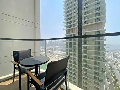 a balcony with a table and chairs and a view of a city at Silkhaus Palm View in Marina Vista Private Beach in Dubai
