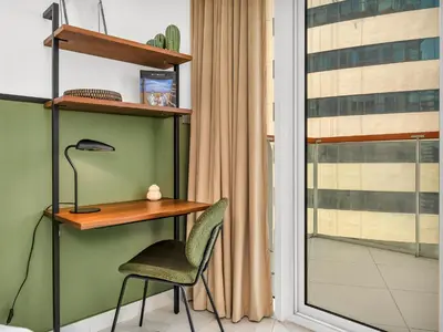 a desk and a chair in a room with a window at Sukoon's Waterfront Two-Bedroom in Dubai