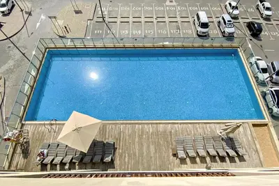 an overhead view of a swimming pool with chairs and an umbrella at Silkhaus Beach Accessible Studio Palm View in Dubai